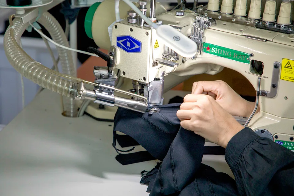 Close-up of hands guiding a garment through an industrial sewing machine — user-provided photograph